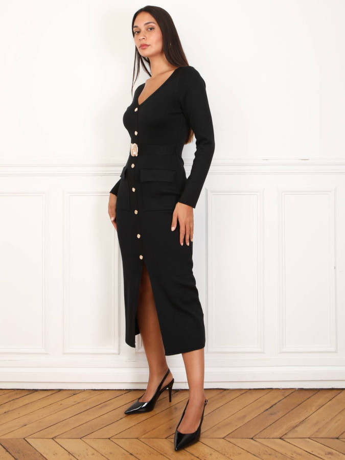 Robe mi-longue noire à boutons et ceinture dorés.