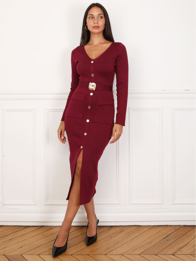 Robe mi-longue bordeaux à boutons et ceinture dorés.